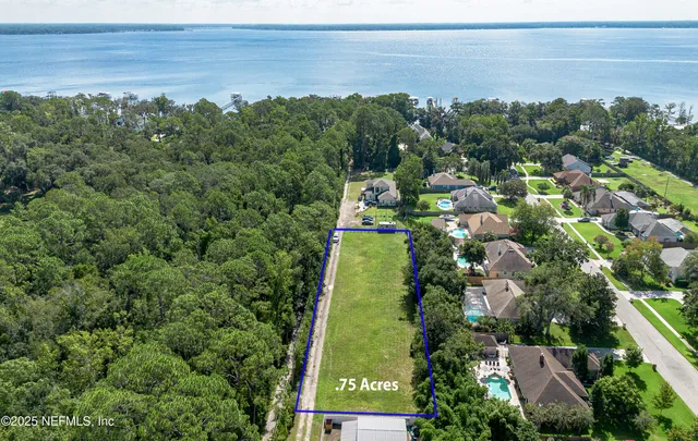 an aerial view of a residential houses with outdoor space and trees all around