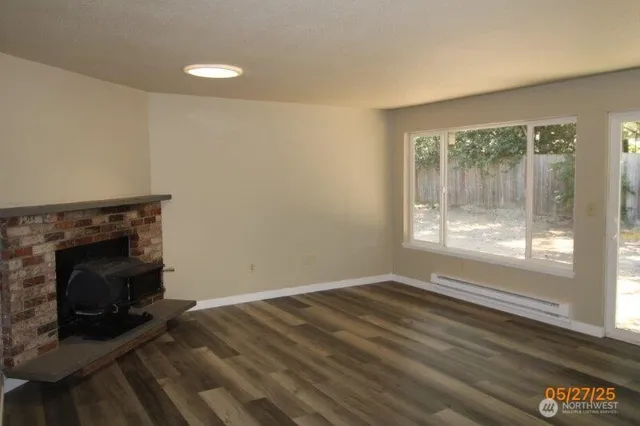 a view of empty room with wooden floor and fireplace