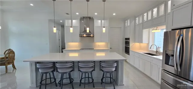 a kitchen with kitchen island granite countertop a table chairs refrigerator and microwave