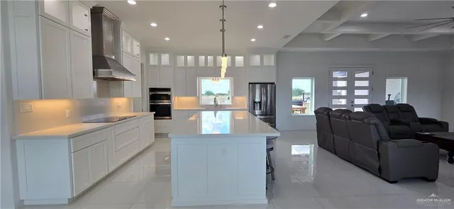 a large kitchen with stainless steel appliances kitchen island a large counter top a stove and a chandelier
