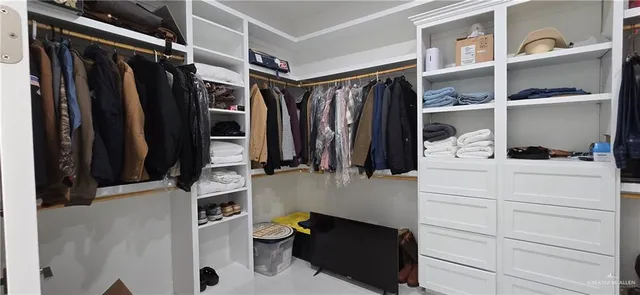 a view of walk in closet with clothes and shoes