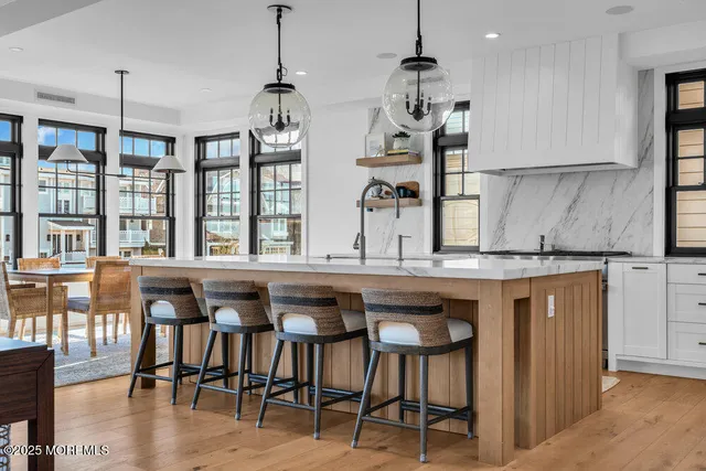 a dining hall with stainless steel appliances granite countertop a dining table chairs stove and white cabinets