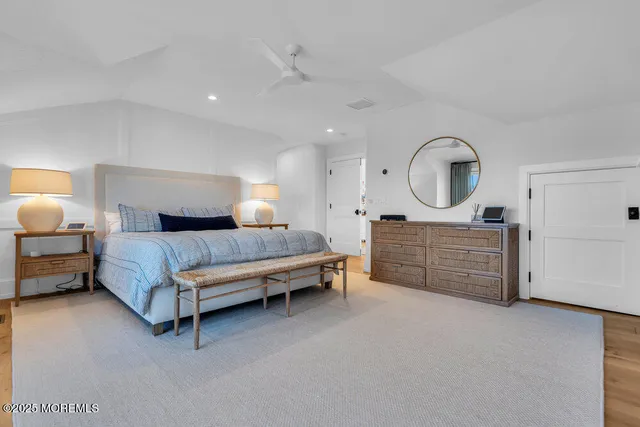 a spacious bedroom with a bed a mirror and dresser