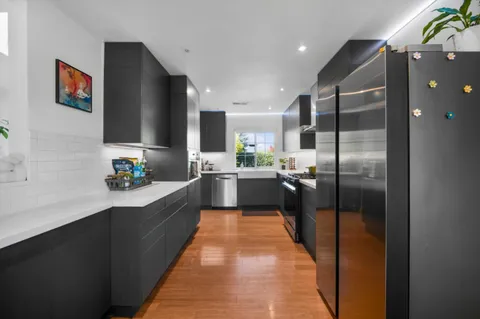 a large kitchen with a large counter top a refrigerator and stainless steel appliances