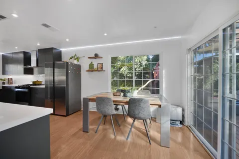 a kitchen with stainless steel appliances wooden floor and chairs