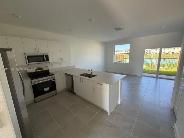 a kitchen with a sink a stove top oven and white cabinets