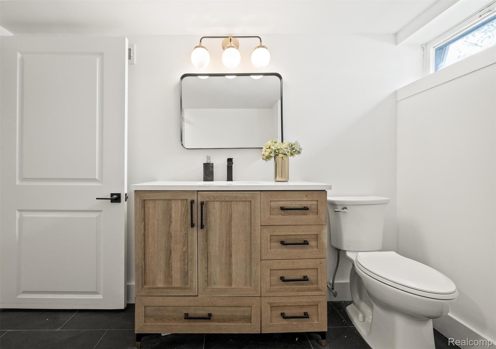 347 Highland Avenue Rochester, MI 48307 - Photo 48 of 59 Bathroom featuring a wood-finish vanity with a white countertop, a black-framed mirror, and a three-light fixture