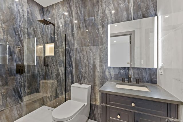 a bathroom with a toilet a sink shower and mirror