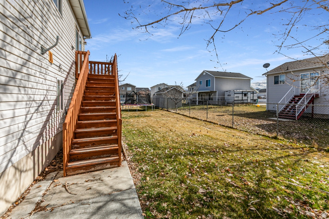 4239 West 5325th Street South Roy, UT 84067 - Photo 23 of 26 Fenced backyard featuring a trampoline, a residential view, and a wooden deck