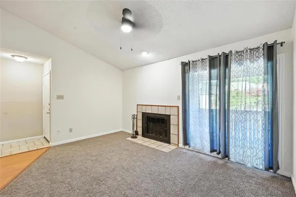 an empty room with fireplace cabinet and windows