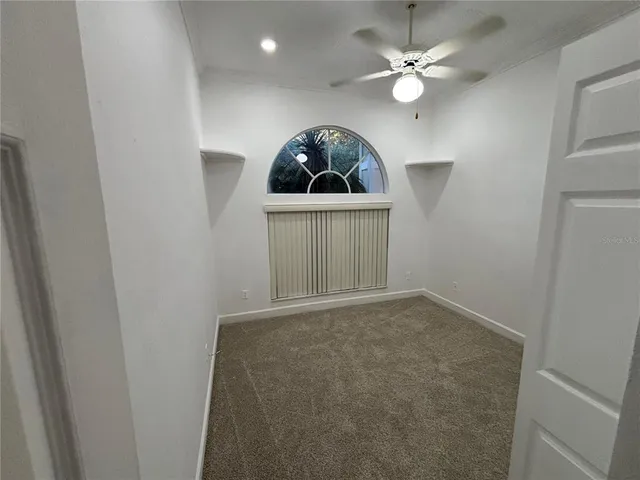an empty room with a chandelier fan and entryway