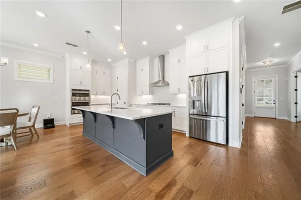a kitchen with stainless steel appliances a refrigerator a stove a sink dishwasher with a dining table and chairs