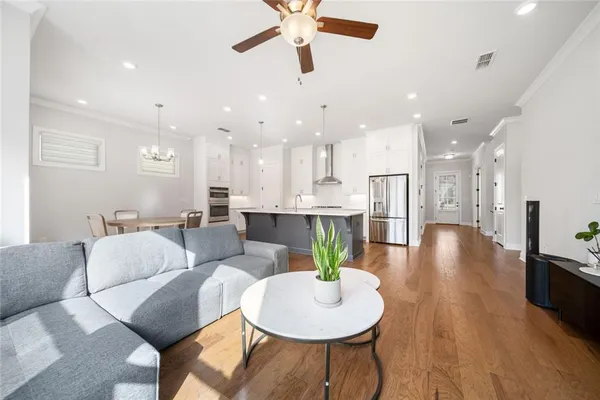 a living room with couches and kitchen view with wooden floor