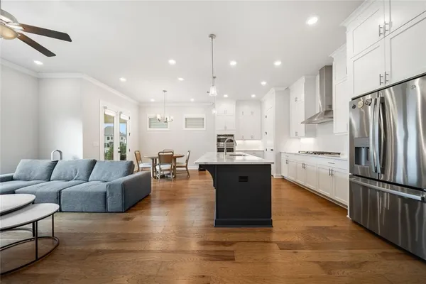 a living room with stainless steel appliances kitchen island granite countertop a refrigerator a stove top oven and a center island