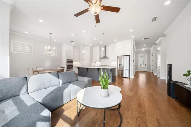 a kitchen with kitchen island a sink stainless steel appliances and living room view