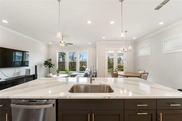 a kitchen with kitchen island a sink stainless steel appliances and living room view