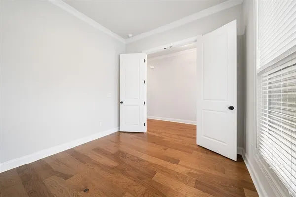 a view of an empty room with wooden floor and a window