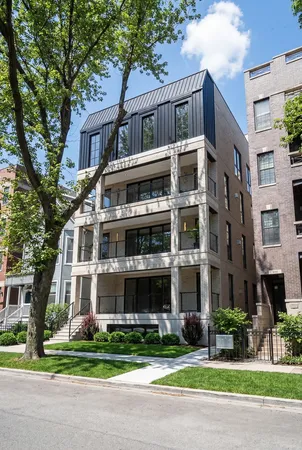 a front view of multi story residential apartment building with yard and traffic signal