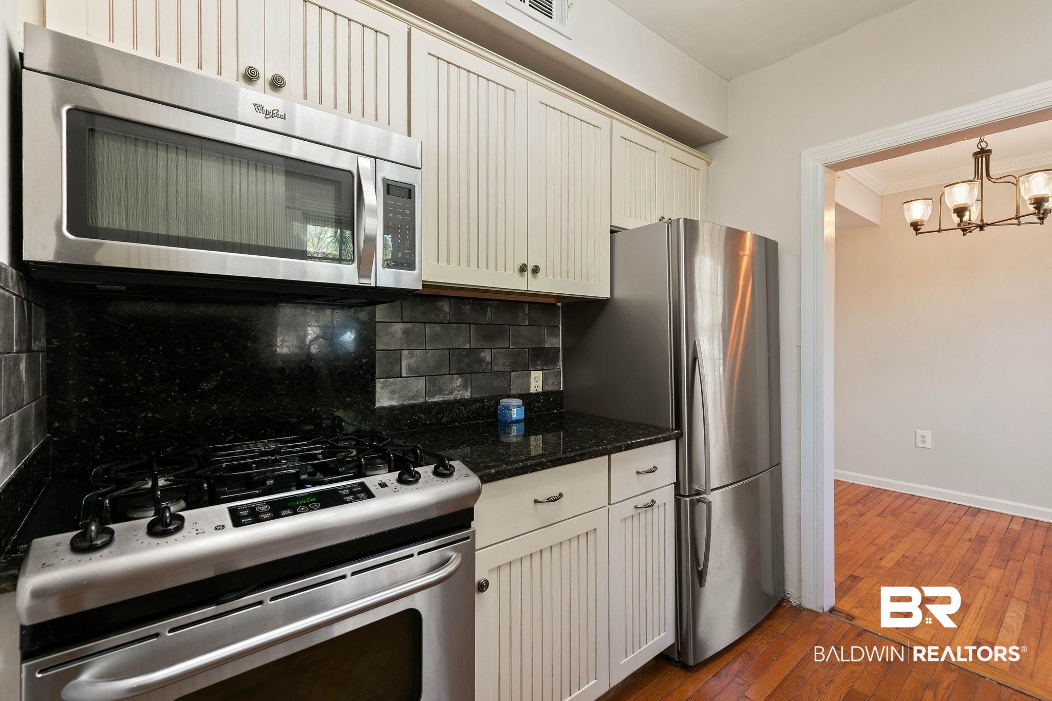 214 Upham Street, Unit 8D Mobile, AL 36607 - Photo 13 of 36 Kitchen featuring stainless steel appliances, dark wood finished floors, ornamental molding, dark stone counters, and backsplash