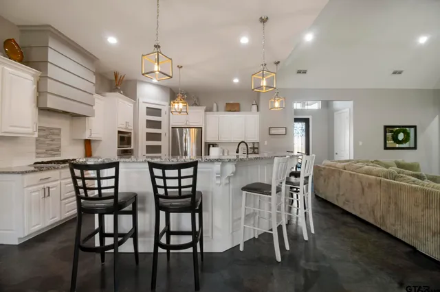 a kitchen with stainless steel appliances kitchen island granite countertop a dining table chairs and sink