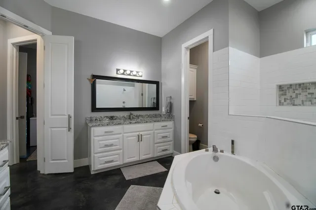 a bathroom with a tub sink and mirror