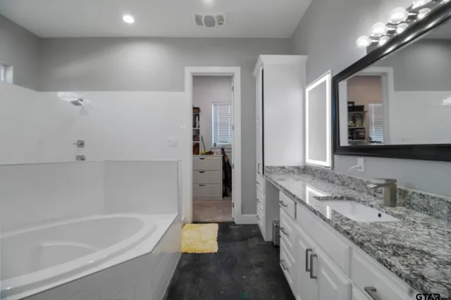 a bathroom with a granite countertop sink mirror and bathtub