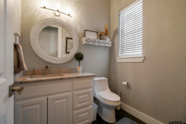 a bathroom with a granite countertop toilet sink and mirror