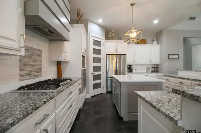 a kitchen with stainless steel appliances granite countertop a stove a sink dishwasher and a refrigerator with wooden floor