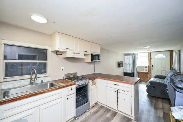a view of a kitchen with cabinets stainless steel appliances and a wooden floor