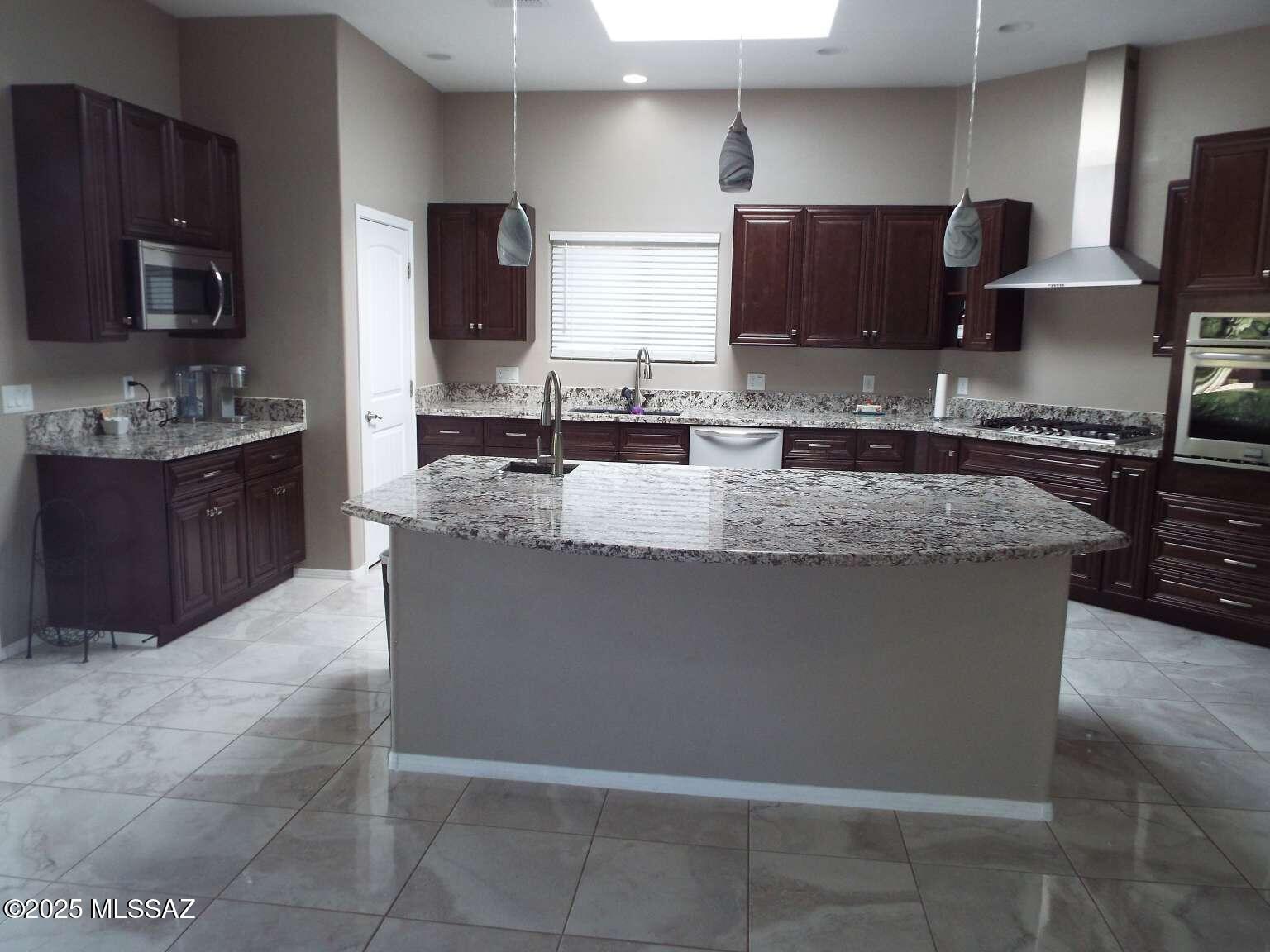 11553 East Tanque Verde Road Tucson, AZ 85749 - Photo 9 of 16 a large kitchen with granite countertop a stove a sink and a microwave