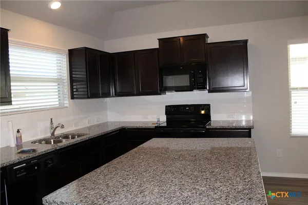 a kitchen with granite countertop a sink and a stove top oven
