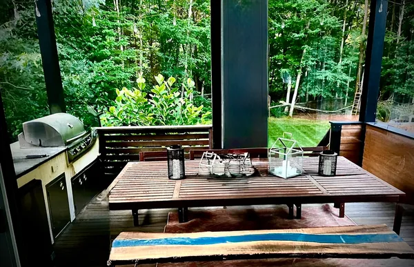 a view of a patio with table and chairs a barbeque with wooden fence and plants