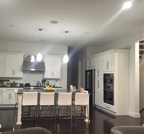 a kitchen with stainless steel appliances granite countertop a stove top oven a sink a dining table and chairs with cabinets