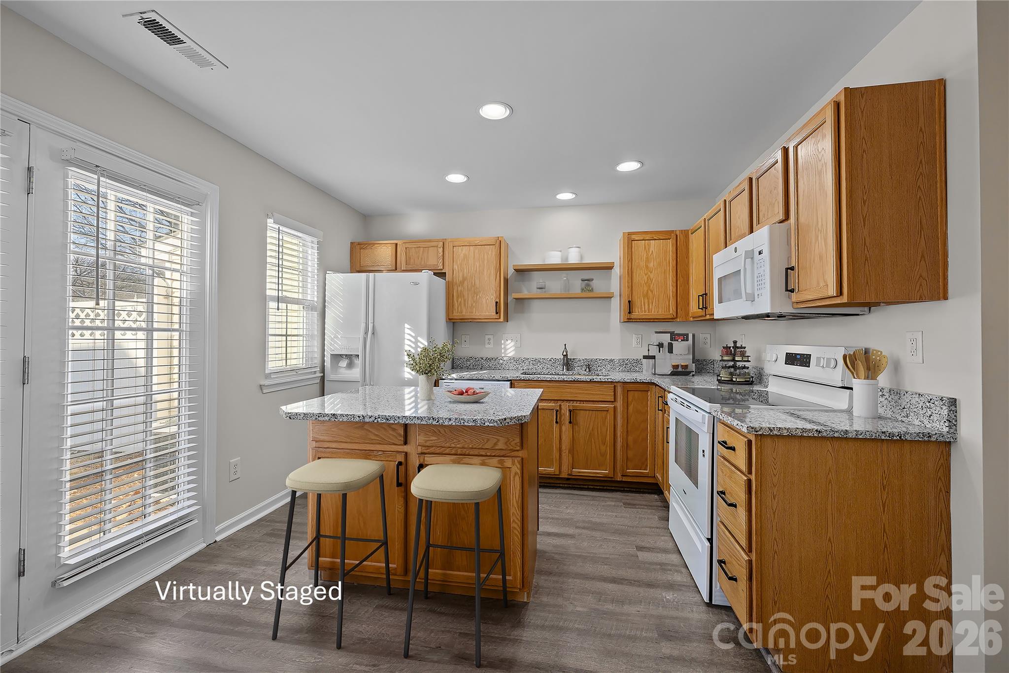 209 Primrose Walk Fort Mill, SC 29715 - Photo 13 of 39 a kitchen with stainless steel appliances granite countertop a sink a stove a refrigerator cabinets and a dining table with wooden floor