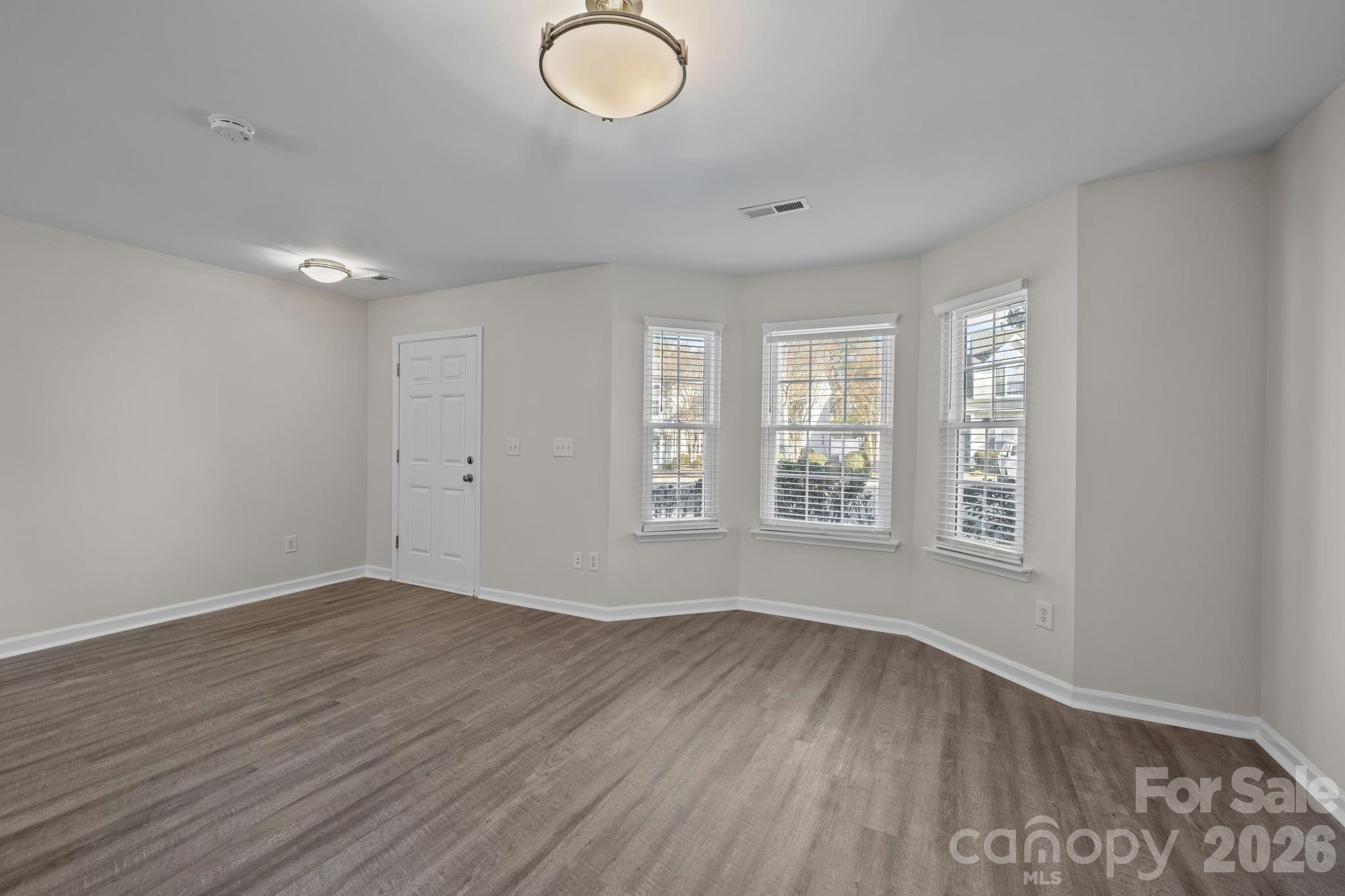 209 Primrose Walk Fort Mill, SC 29715 - Photo 9 of 39 an empty room with wooden floor and windows