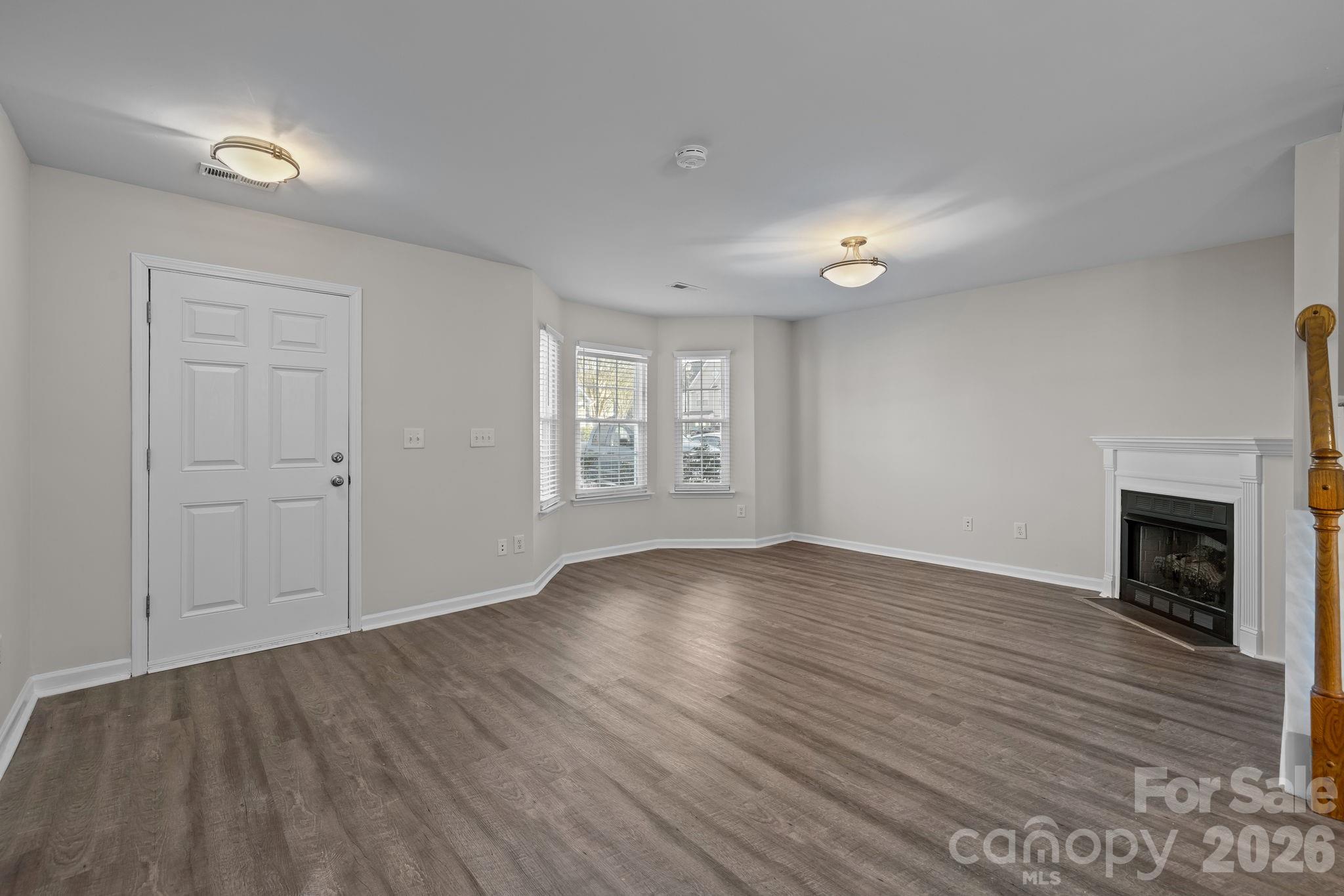209 Primrose Walk Fort Mill, SC 29715 - Photo 10 of 39 an empty room with wooden floor fireplace and windows
