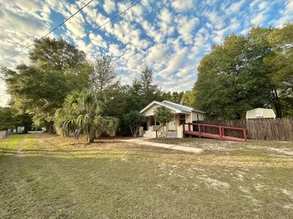 a view of a house with a yard and large trees