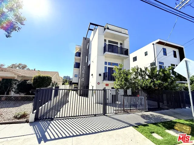 a view of a white building with wooden floor next to a yard