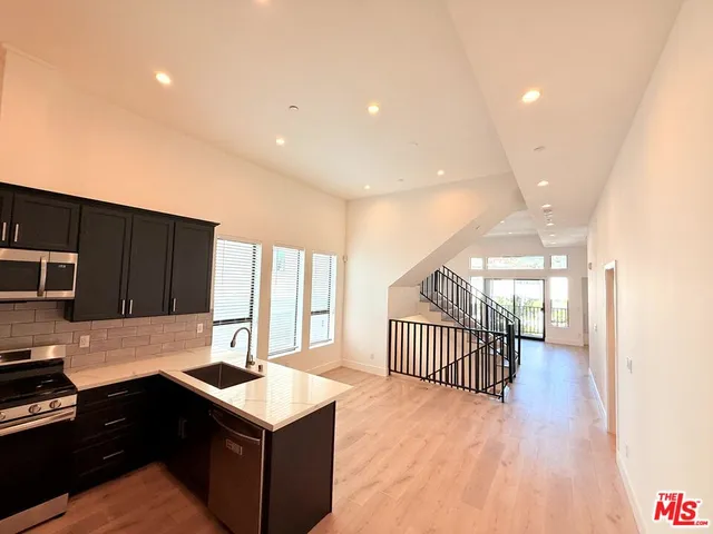 a kitchen with a refrigerator a sink dishwasher with a dining table and wooden floor
