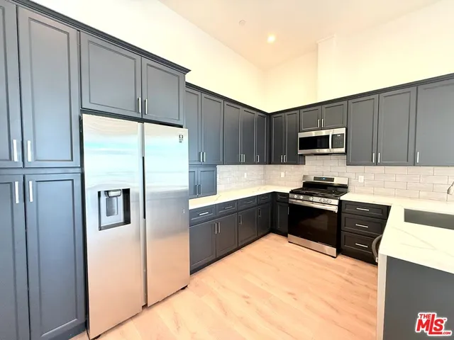 a large kitchen with granite countertop a refrigerator stove and microwave