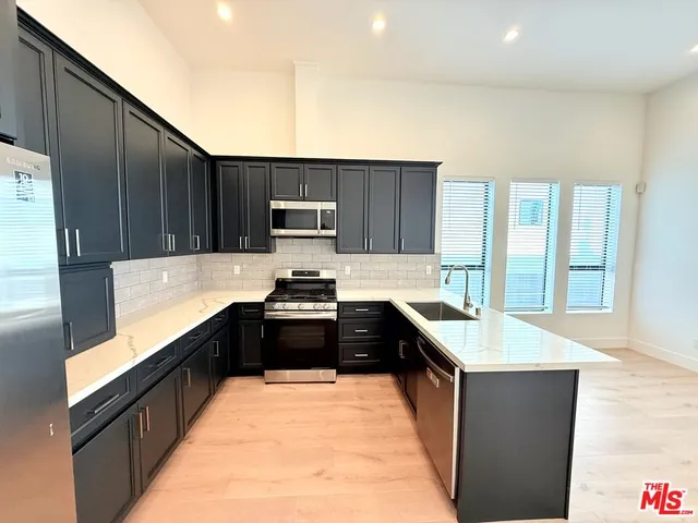 a large kitchen with kitchen island granite countertop a sink and a stove top oven with wooden floor