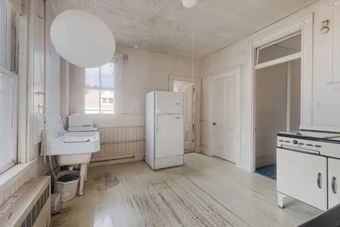 a kitchen with a refrigerator and wooden floor