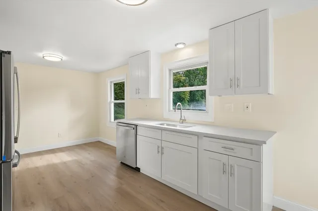 a view of cabinets a sink wooden floor and windows in a room