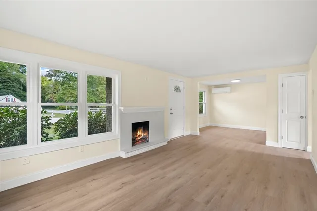 a view of empty room with wooden floor and fireplace