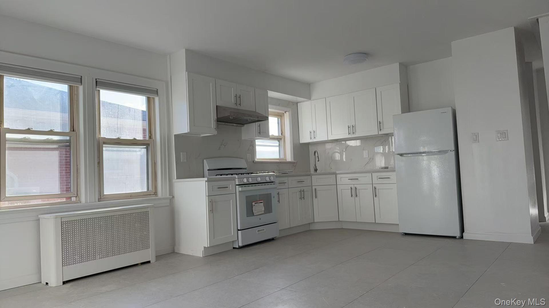 40-14 190th Street, Unit 2 Queens, NY 11358 - Photo 2 of 6 a kitchen with stainless steel appliances granite countertop a refrigerator a stove and a sink with large window