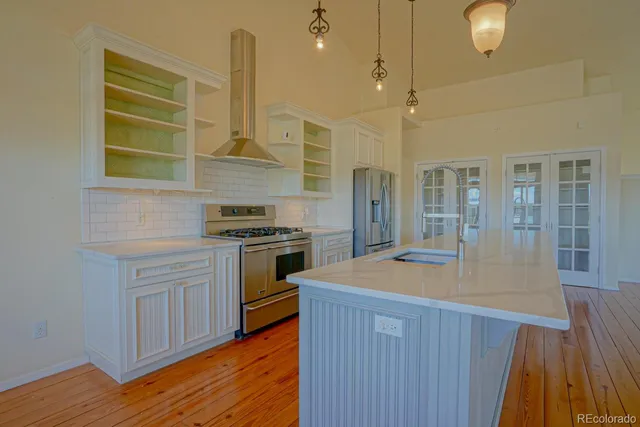 a kitchen with stainless steel appliances granite countertop a sink a stove and a wooden floors