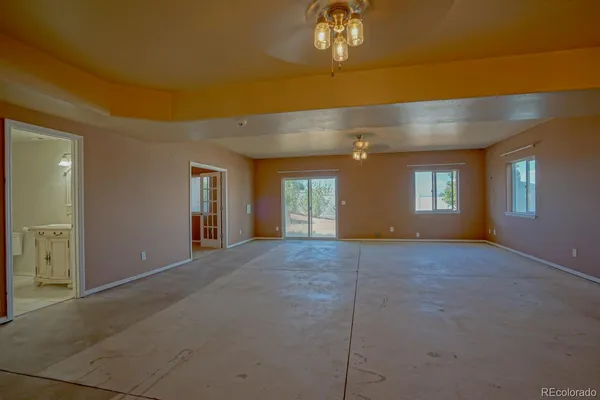 a view of an empty room and chandelier fan