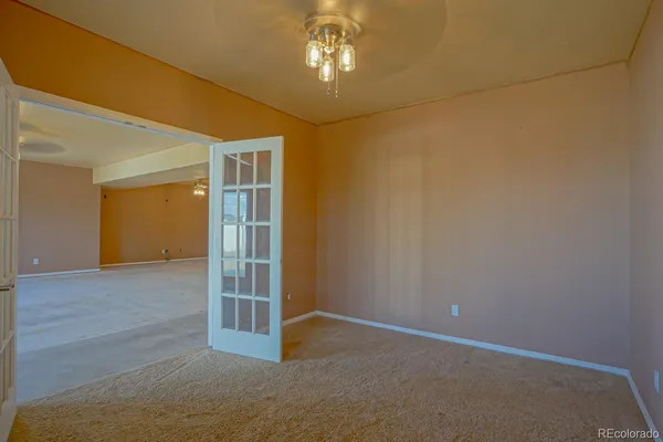 an empty room with chandelier fan and windows