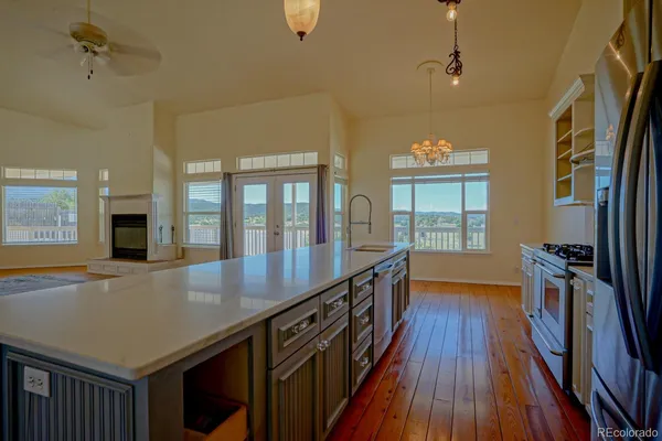 a view of a kitchen with stainless steel appliances granite countertop a refrigerator a stove and a wooden floors