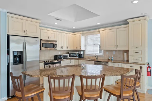 a kitchen with stainless steel appliances granite countertop a stove top oven a refrigerator a sink and white cabinets